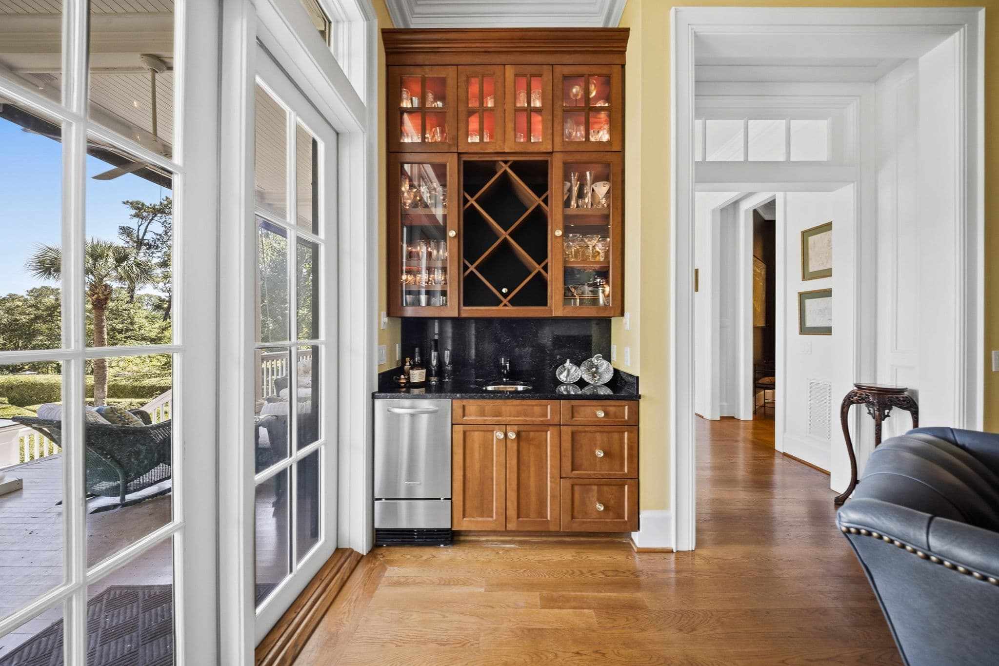 Wet bar with glass cabinets, a diamond wine rack, granite counter, and stainless ice maker beside glass doors to a screened porch.