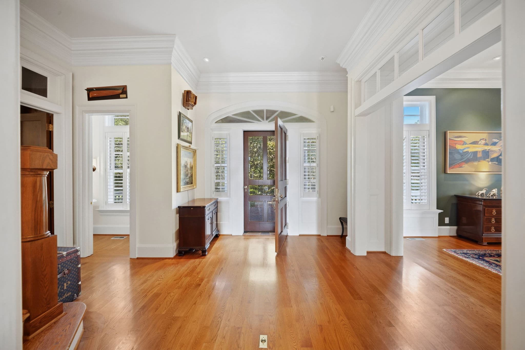 Entry foyer with the wood front door open, arched transom window above, and hardwood floors.