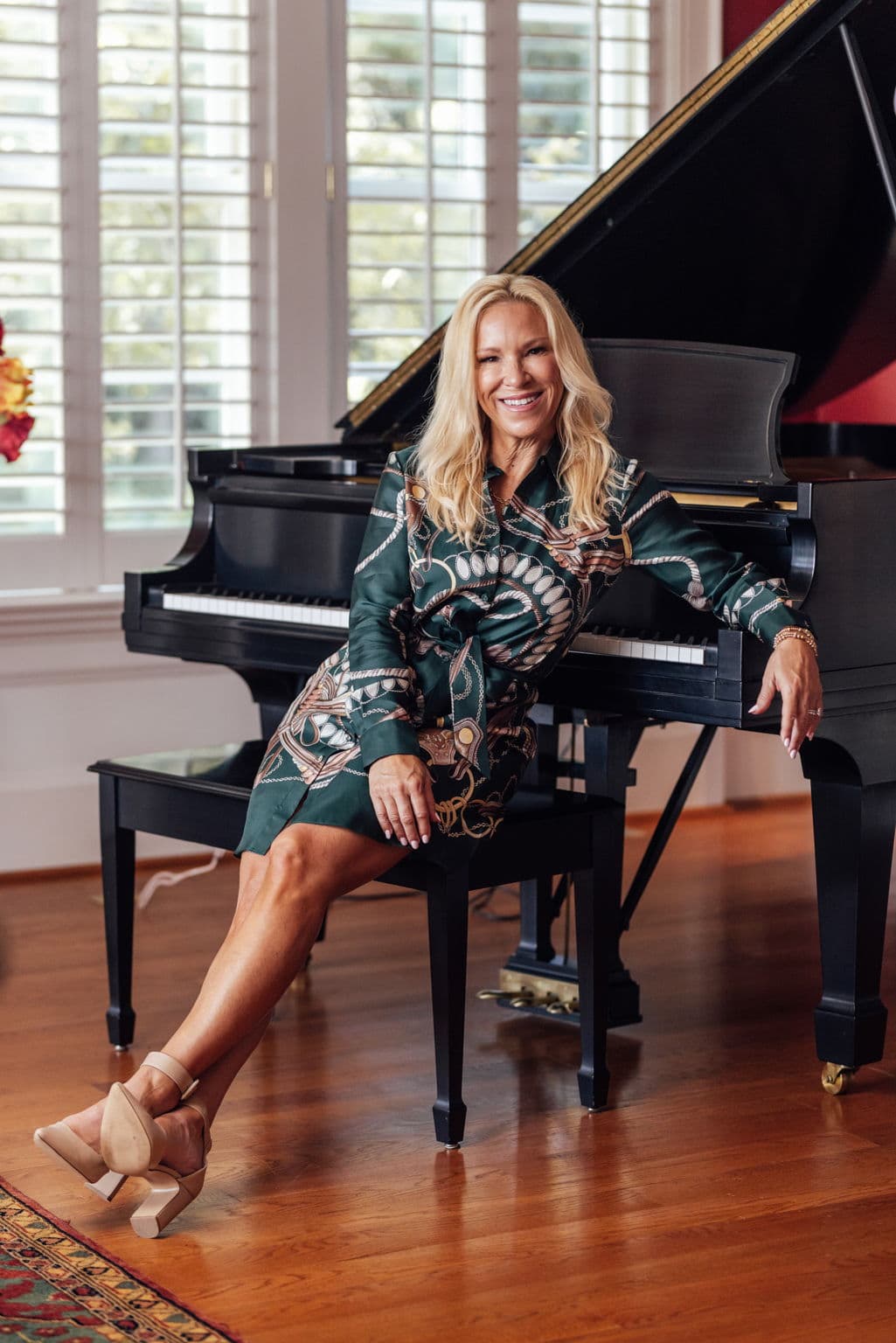 Linda Shafer, seated at a grand piano, leaning back against it, smiling at the camera