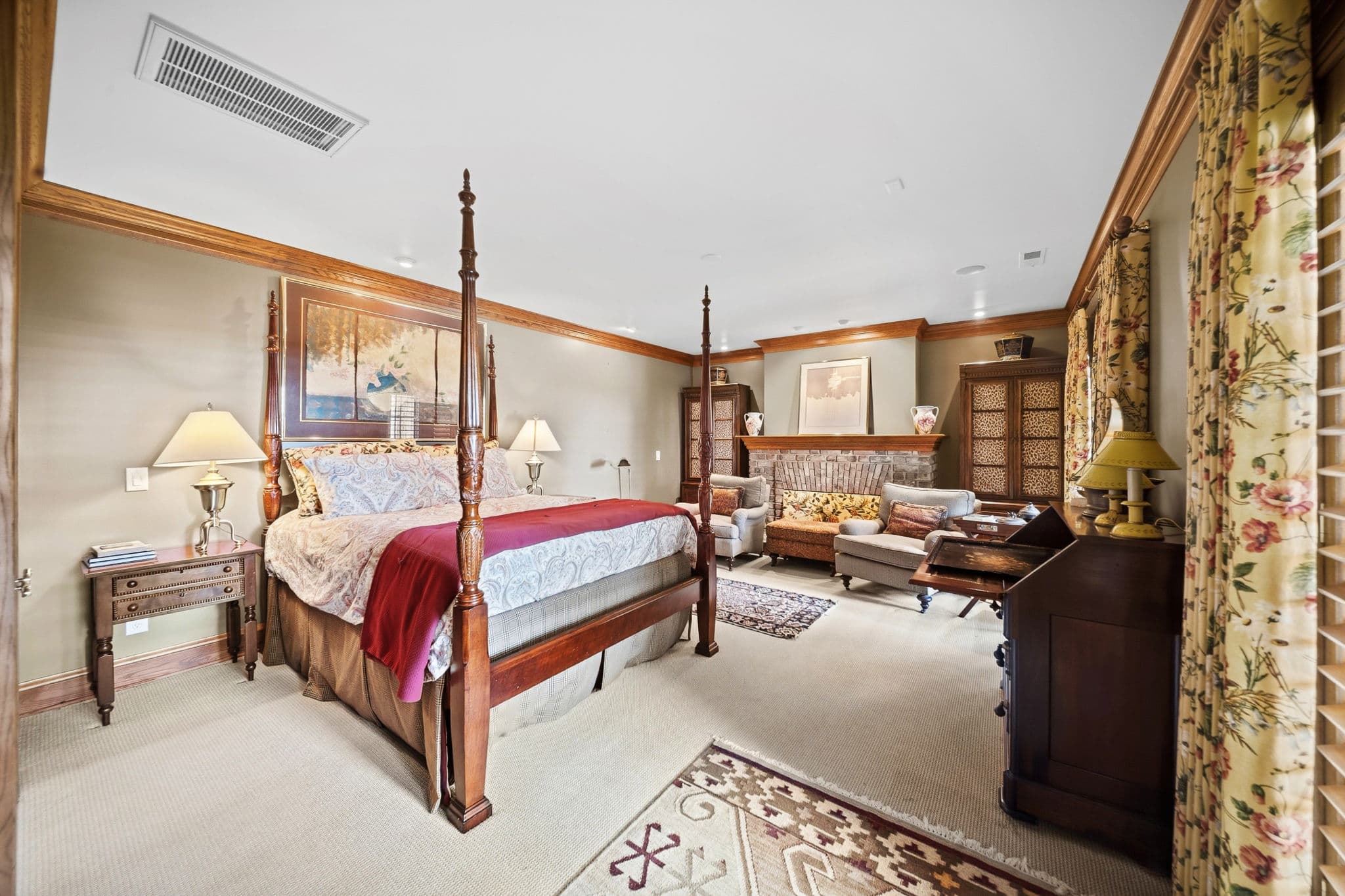 Bedroom with four-poster bed, red throw blanket, brick fireplace, and leopard-print cabinet doors.