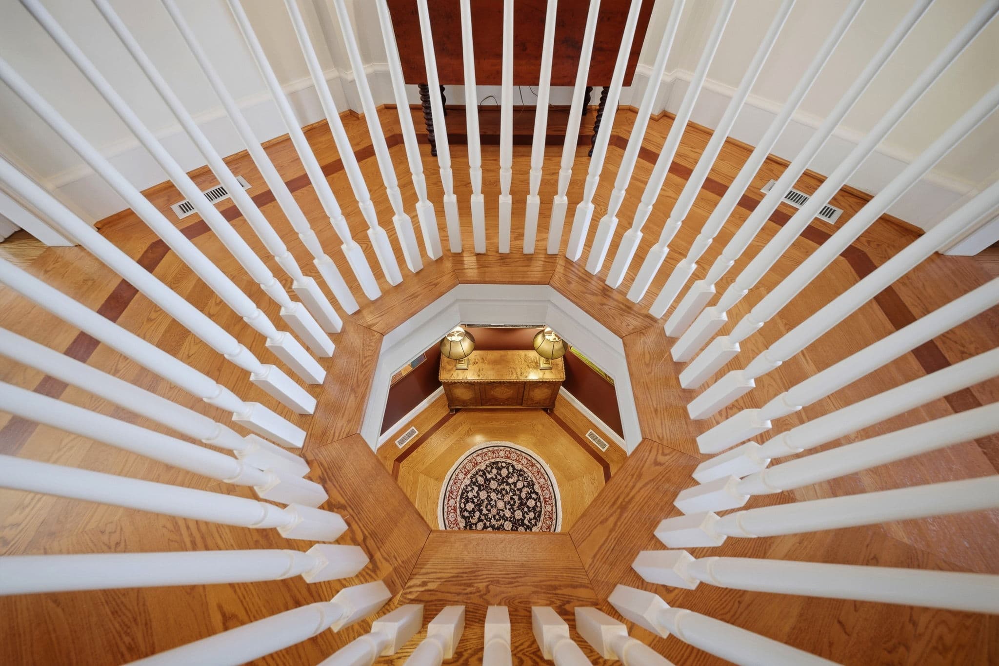 Downward view through an octagonal stair railing to the entry foyer below.