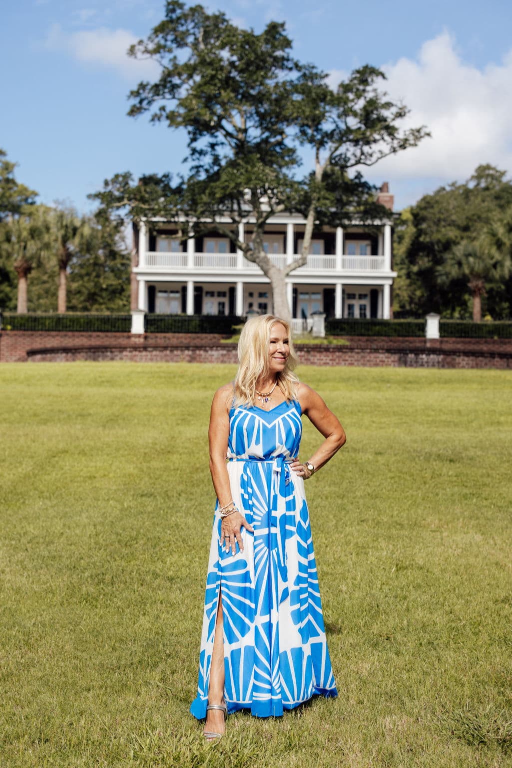 Linda Shafer — standing on a lawn in front of a large white-columned house, hand on hip